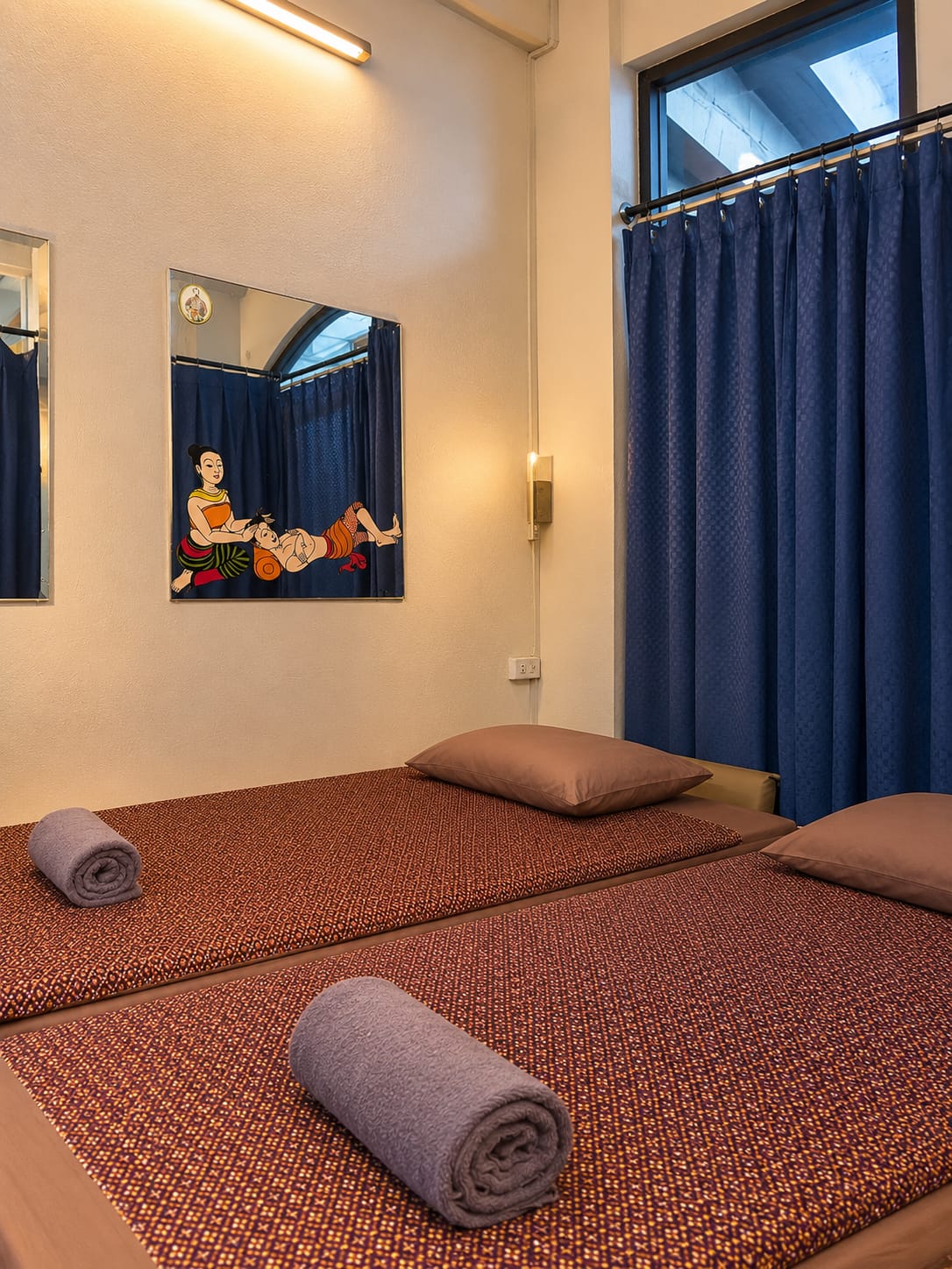 เตียงนวดไทย ข้างภาพวาดท่านวดแผนไทยโบราณ